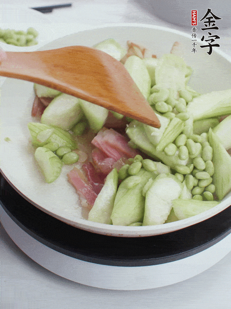 依次下絲瓜、青豆翻炒，炒至絲瓜打蔫縮小。