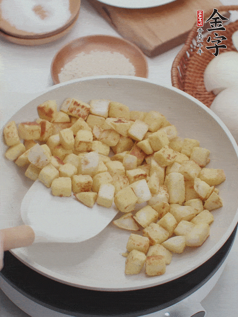 起鍋熱油，倒入饅頭丁，小火煎至蛋液凝固定型再翻面，饅頭丁部煎至金黃時盛起待用。