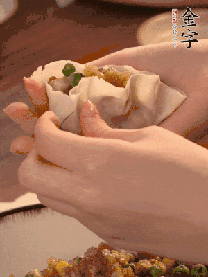 取一大勺餡料放進(jìn)餃子皮里，用大拇指按住頂部餡料，再用虎口掐出形狀。